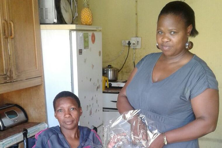 A Buckets of Hope food parcel handed to a woman using a wheelchair at her home
