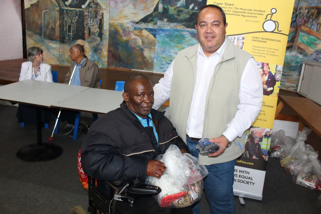 A CTAPD staff member handing relief parcels to a member in a wheelchair at a community handover